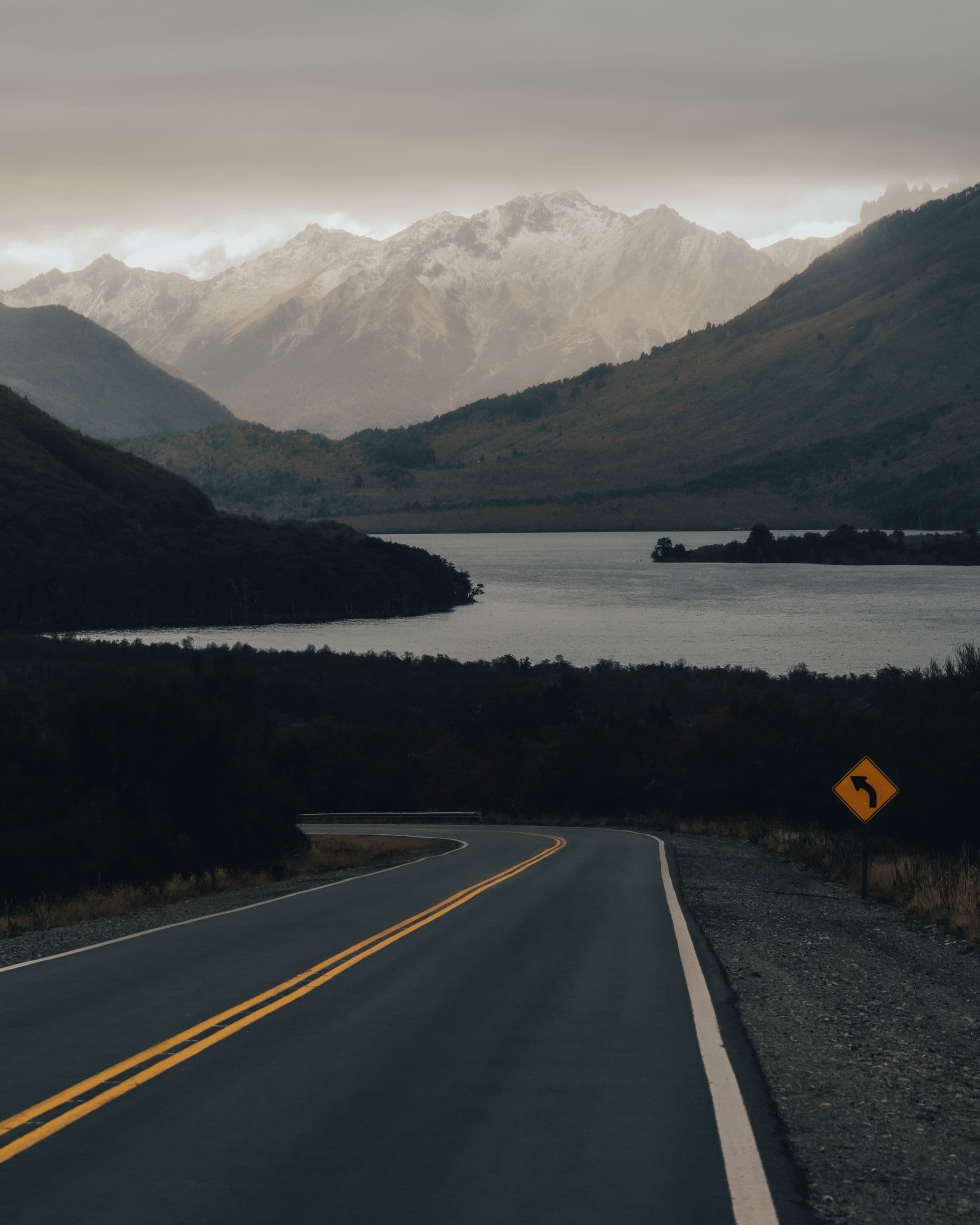 Winding road leading through Iceland's mountains beside a tranquil lake